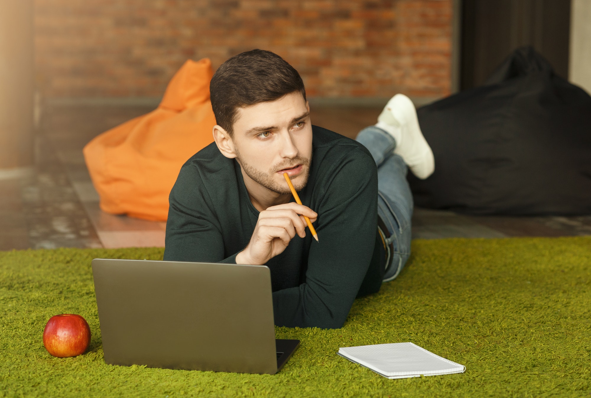 Guy Using Laptop Thinking Lying On Floor In Coworking Workspace