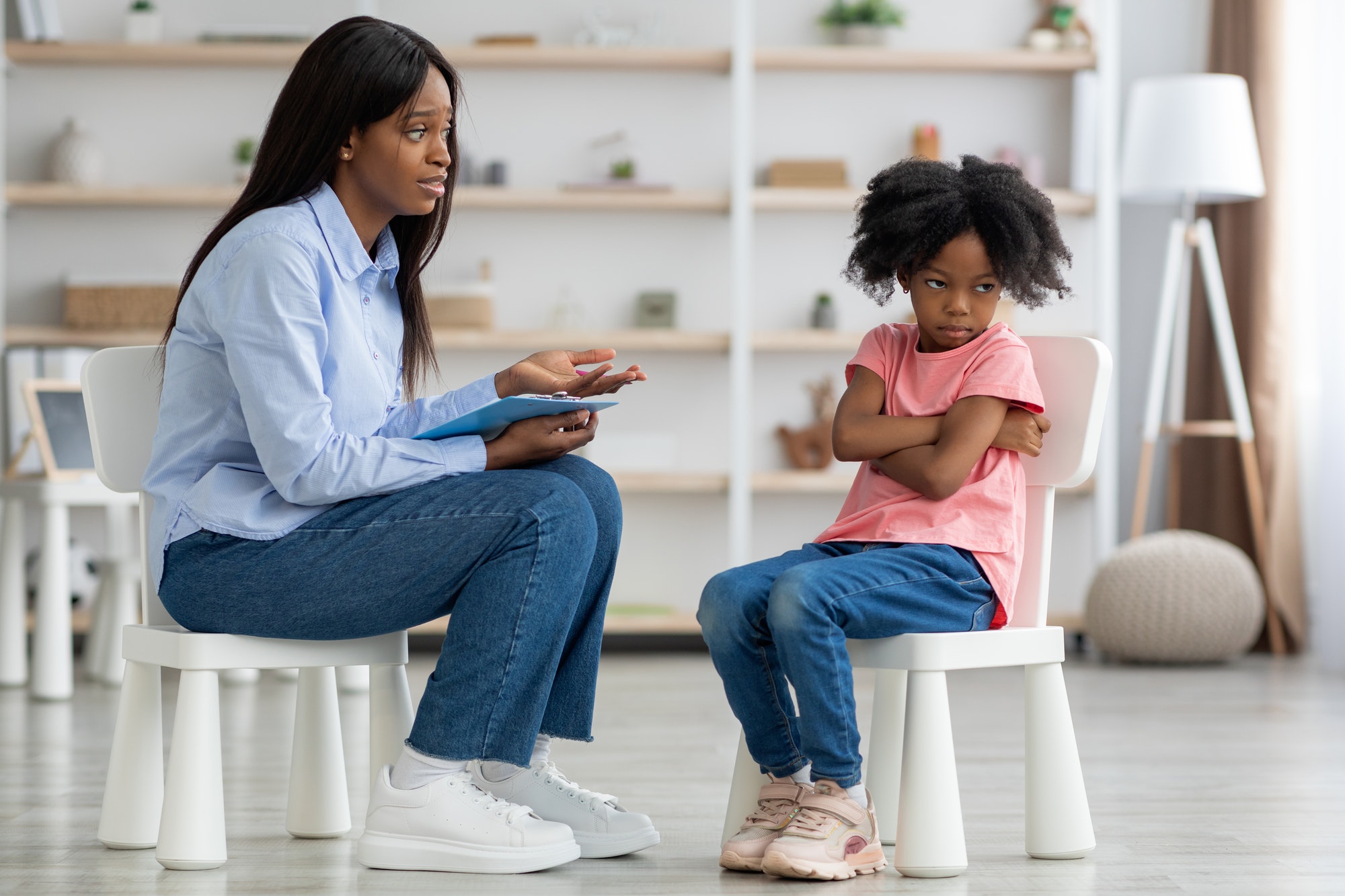 Child psychologist having conversation with defiant little girl