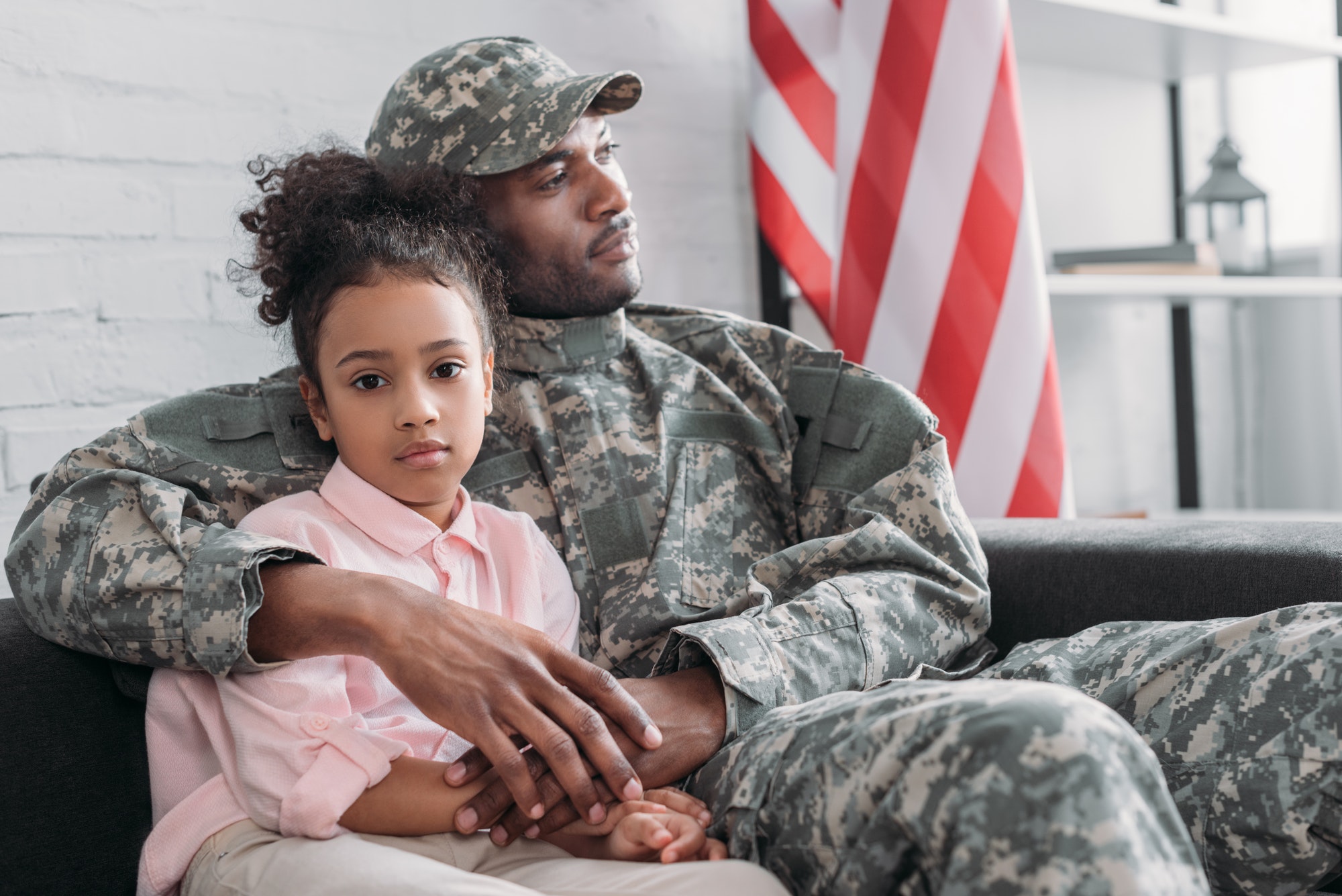 Father in army uniform hugging african american daughter