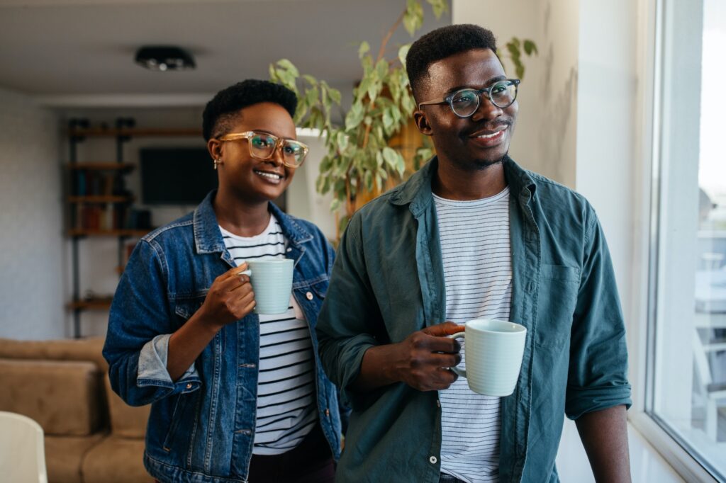 Black couple relaxing at home and drinking coffee