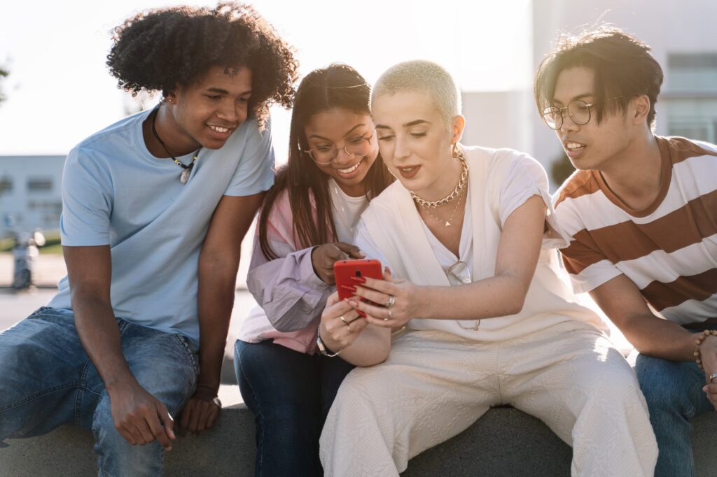 Group of friends sitting together using mobile phones to share content on social media