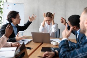 Business People Having Conflict Shouting At Unhappy Businesswoman At Workplace