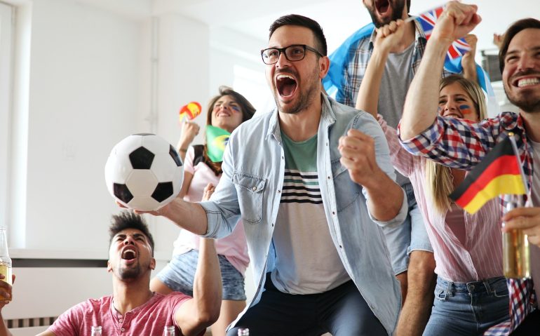 Young group of friends watching sport on television